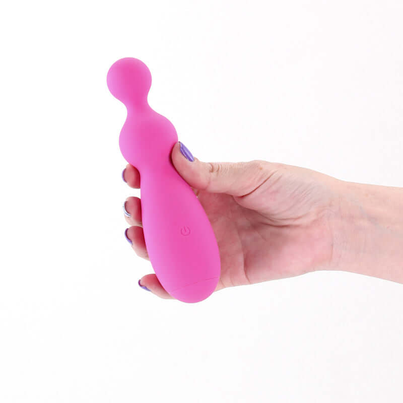 Hand holding the Pretty in Petal USB rechargeable silicone vibrator in vibrant pink color.