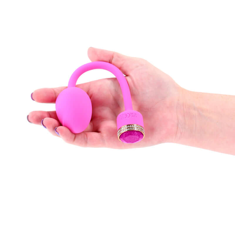 Hand holding a pink USB rechargeable vibrator with a sleek design and jewel accents