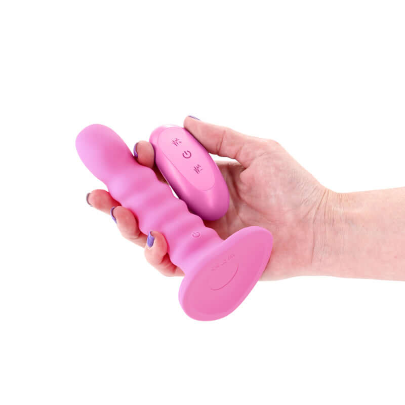 5 inch vibrating dildo with remote in hand, showcasing ribbed design and wireless control.