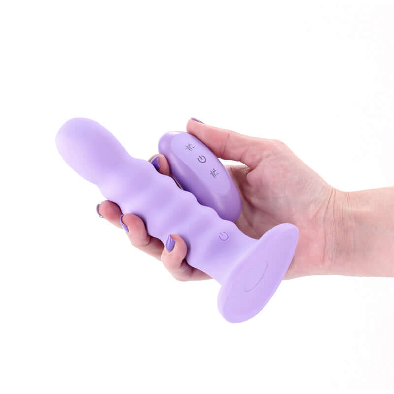 ribbed vibrating dildo with remote held in hand, USB rechargeable with a suction cup base.