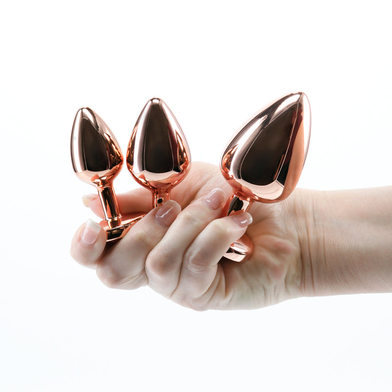 Rear Assets Trainer Kit -  - Pink Heart -  Metallic Butt Plugs with Pink Hearts - Set of 3 Sizes held in hand.