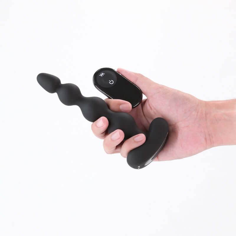 Renegade Reign - 17.9 cm USB rechargeable vibrating anal beads with wireless remote held in hand.