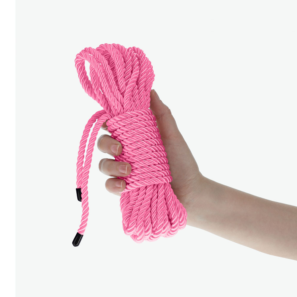 OUCH! Bondage Rope - 10 M -  -  Nylon Bondage Rope - 10 metre Length in pink, held in a hand.