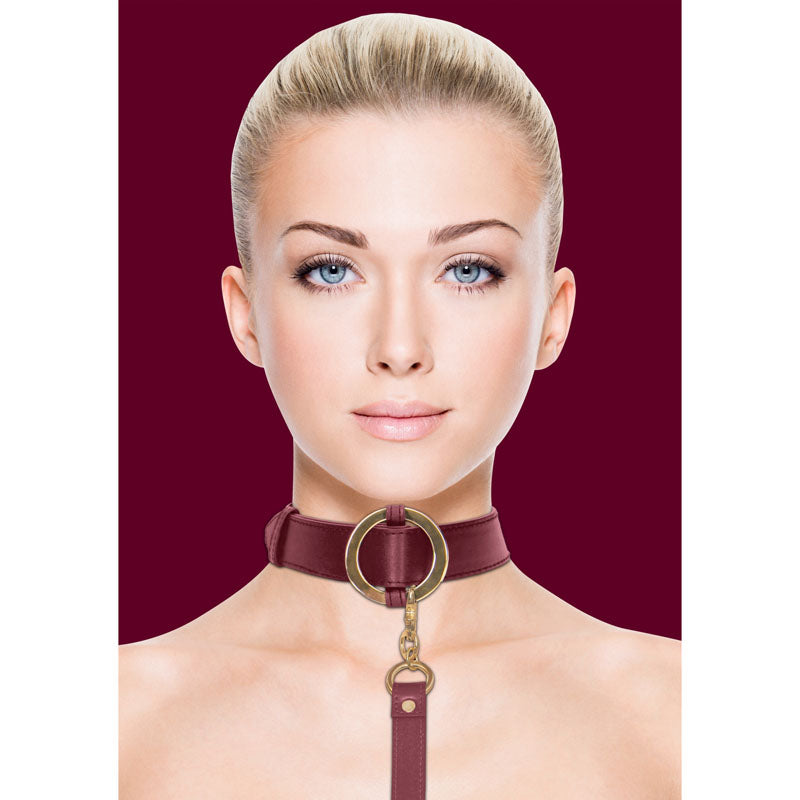 Woman wearing OUCH! Halo - Collar With Leash - Burgundy Restraint with gold details, showcasing luxury BDSM style.