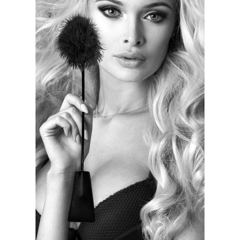 Model holding a OUCH! feather tickler crop, showcasing its soft feathers and sleek design, perfect for playful teasing.