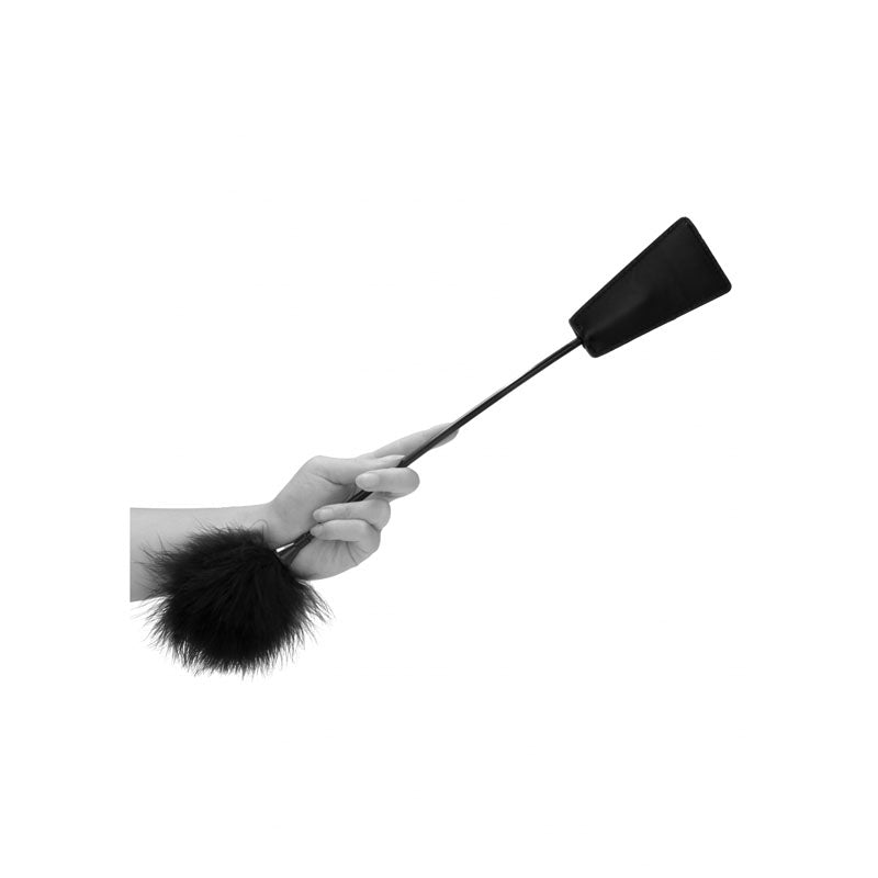 Hand holding OUCH! white crop with feather tickler crop featuring fluffy black feathers, ideal for playful teasing and intimate moments.