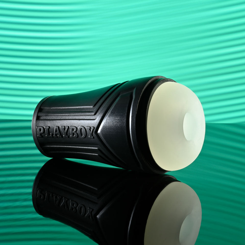 Playboy Pleasure THE URGE SMALL - Clear Small Stroker on a reflective surface, with a textured black canister.