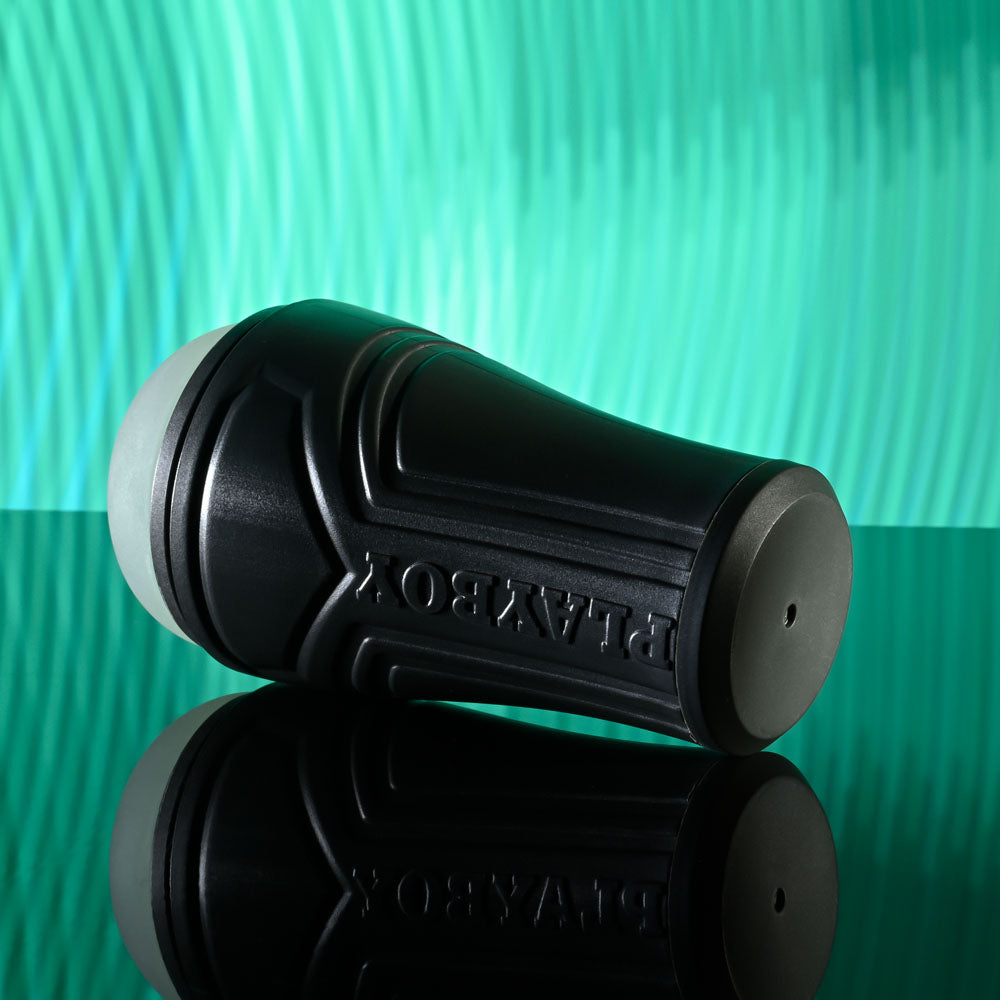 Playboy Pleasure THE URGE SMALL - Clear Small Stroker on a reflective surface with a colorful background.