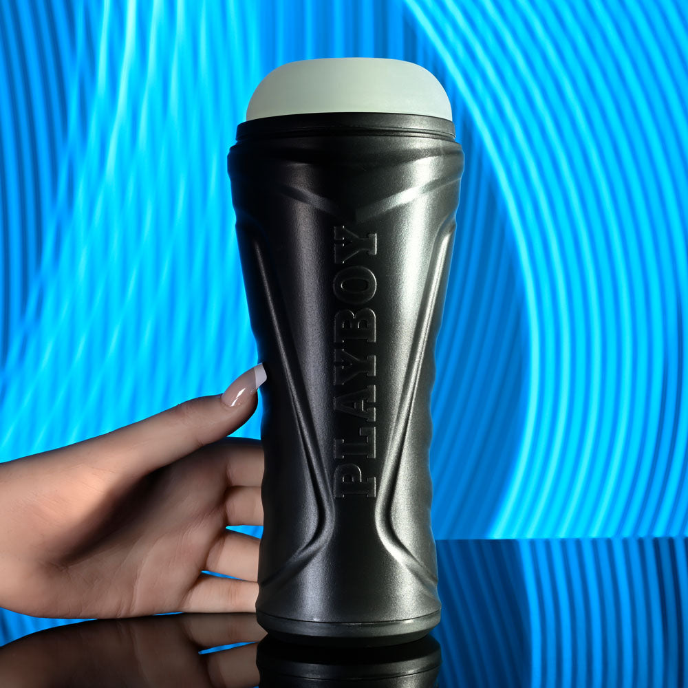 Playboy Pleasure THE URGE MEDIUM - Clear Stroker held in hand with a blue wave background.