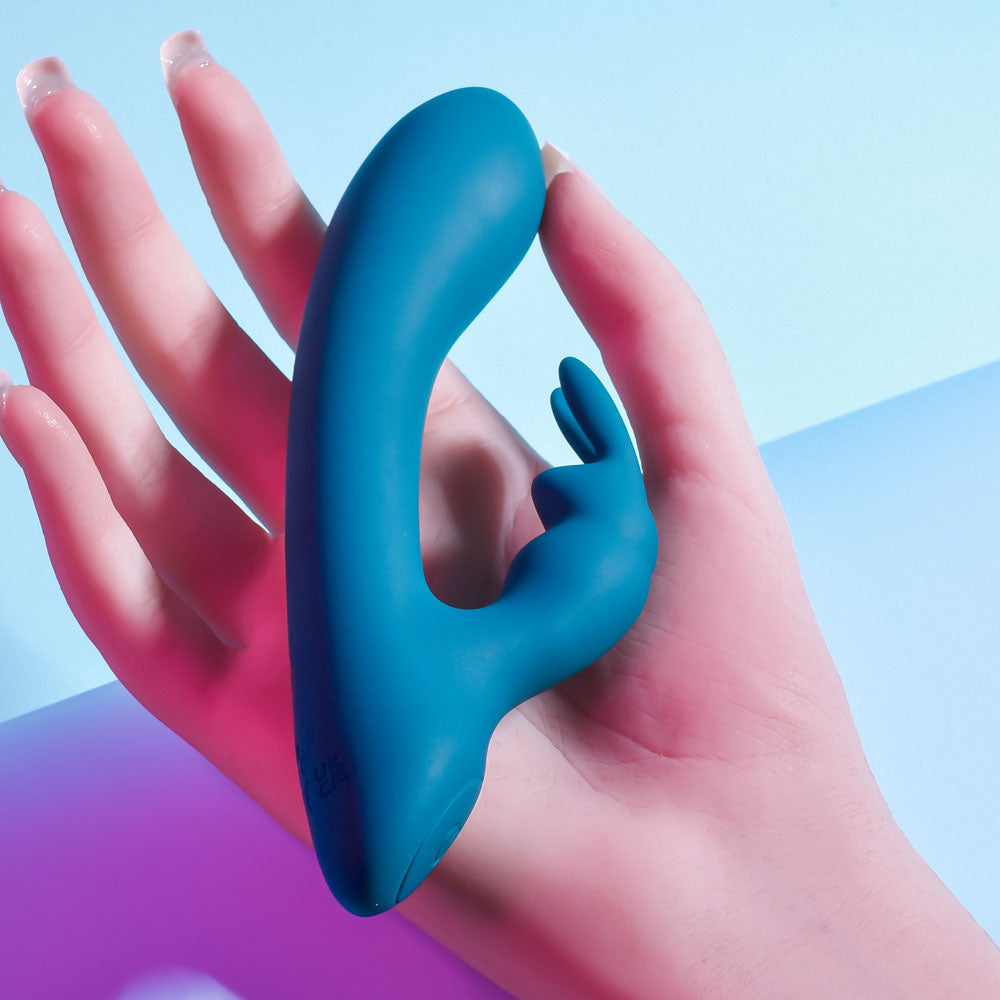 Playboy Pleasure LIL RABBIT - Deep Teal 14.6 cm USB Rechargeable Rabbit Vibrator in hand on colorful background.