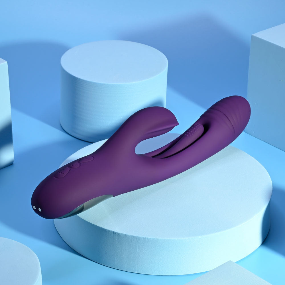 Playboy Pleasure THE THRILL - 24.4 cm USB rechargeable rabbit vibrator on a blue background with geometric shapes.