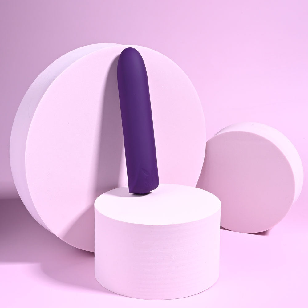 Playboy Pleasure ONE & ONLY - 12 cm USB Rechargeable Bullet against a pastel backdrop with circular shapes.