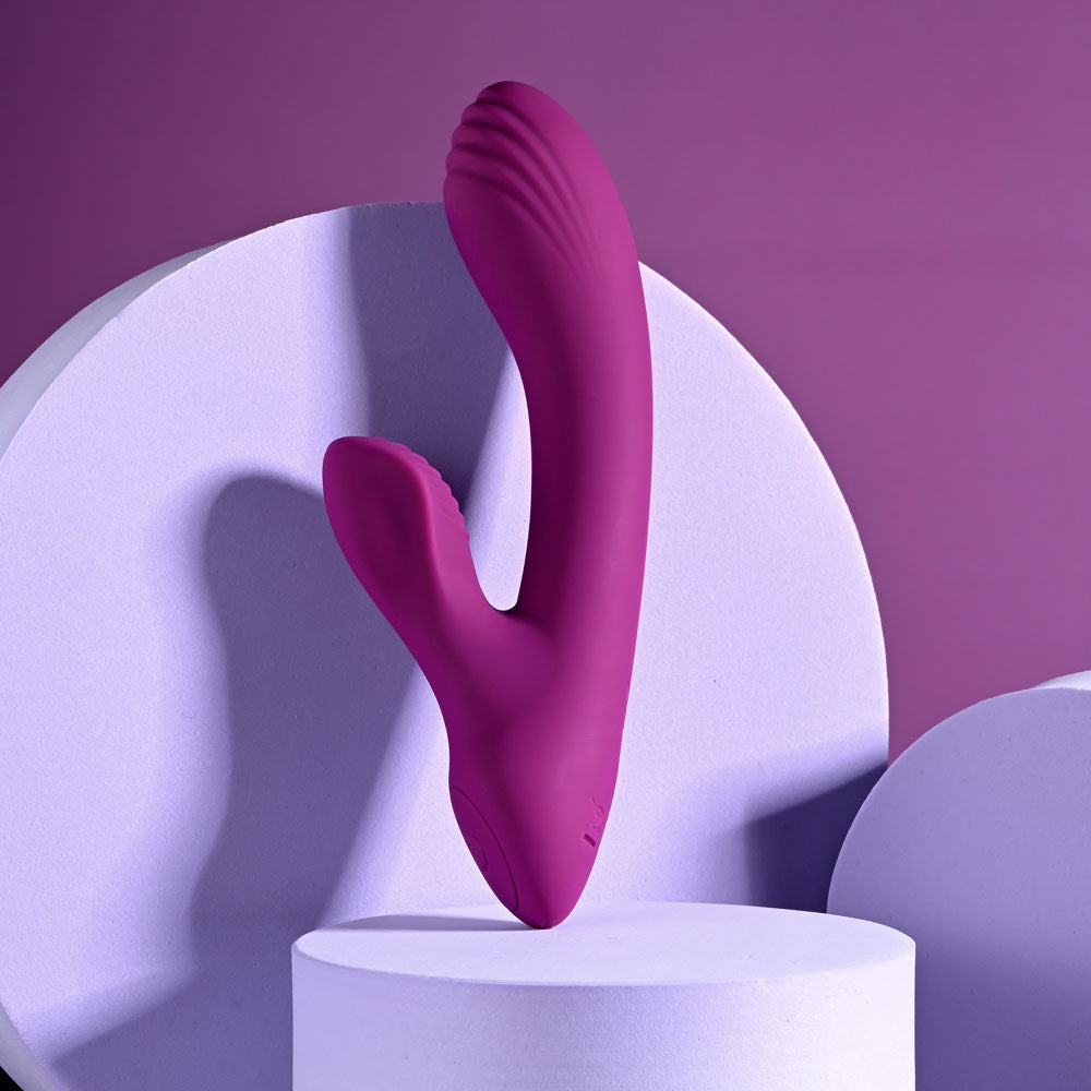 Playboy Pleasure BITTY BUNNY, a 14.7 cm USB rechargeable rabbit vibrator on display against a purple backdrop.