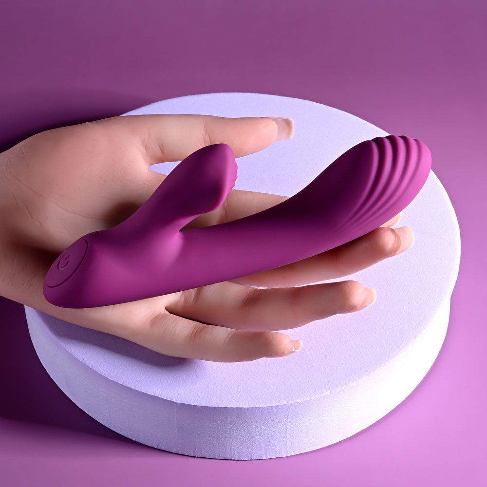 Playboy Pleasure BITTY BUNNY - 14.7 cm USB Rechargeable Rabbit Vibrator in a hand on a purple background.