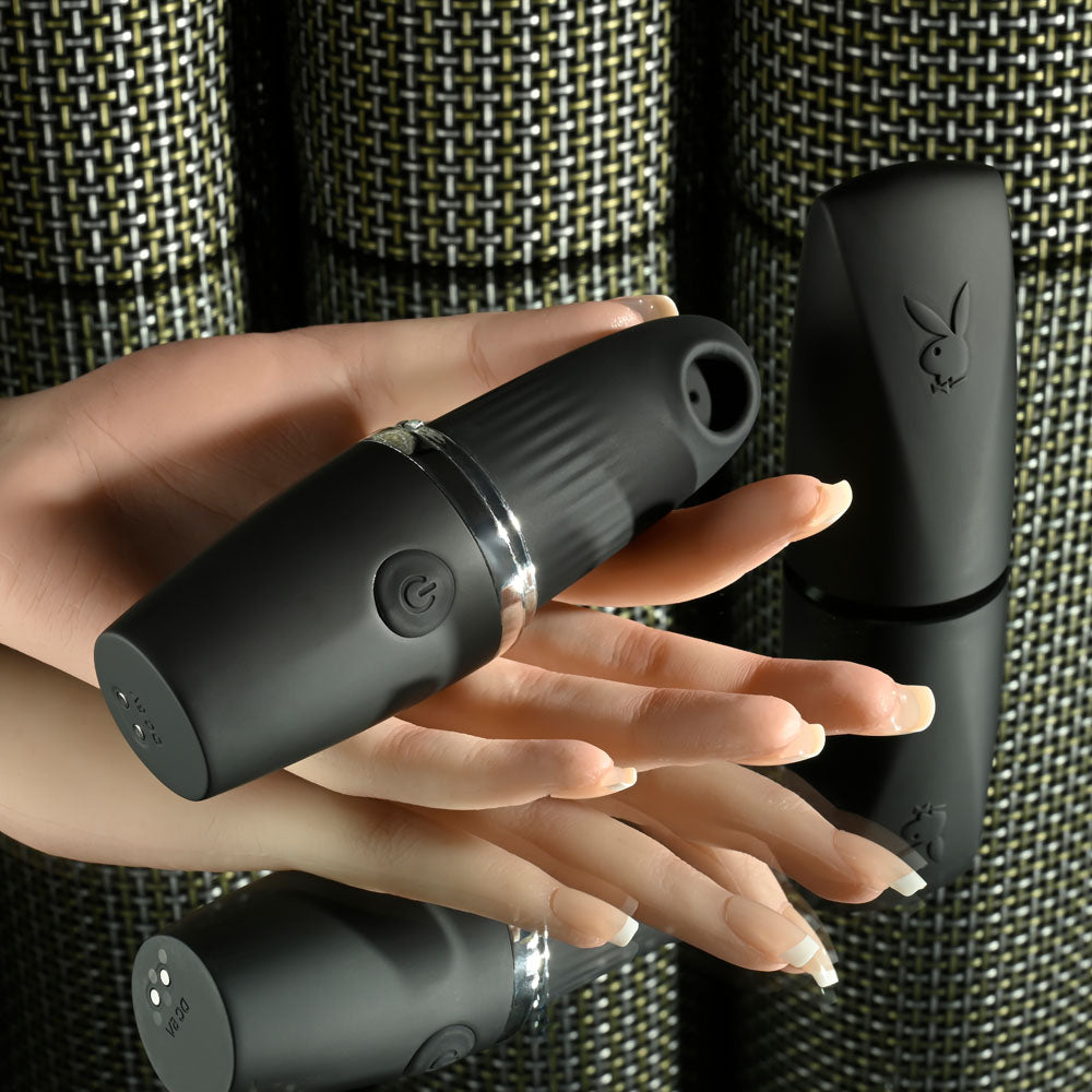 Playboy Pleasure EXCURSION USB rechargeable suction stimulator held in hand with sleek design and stylish base.