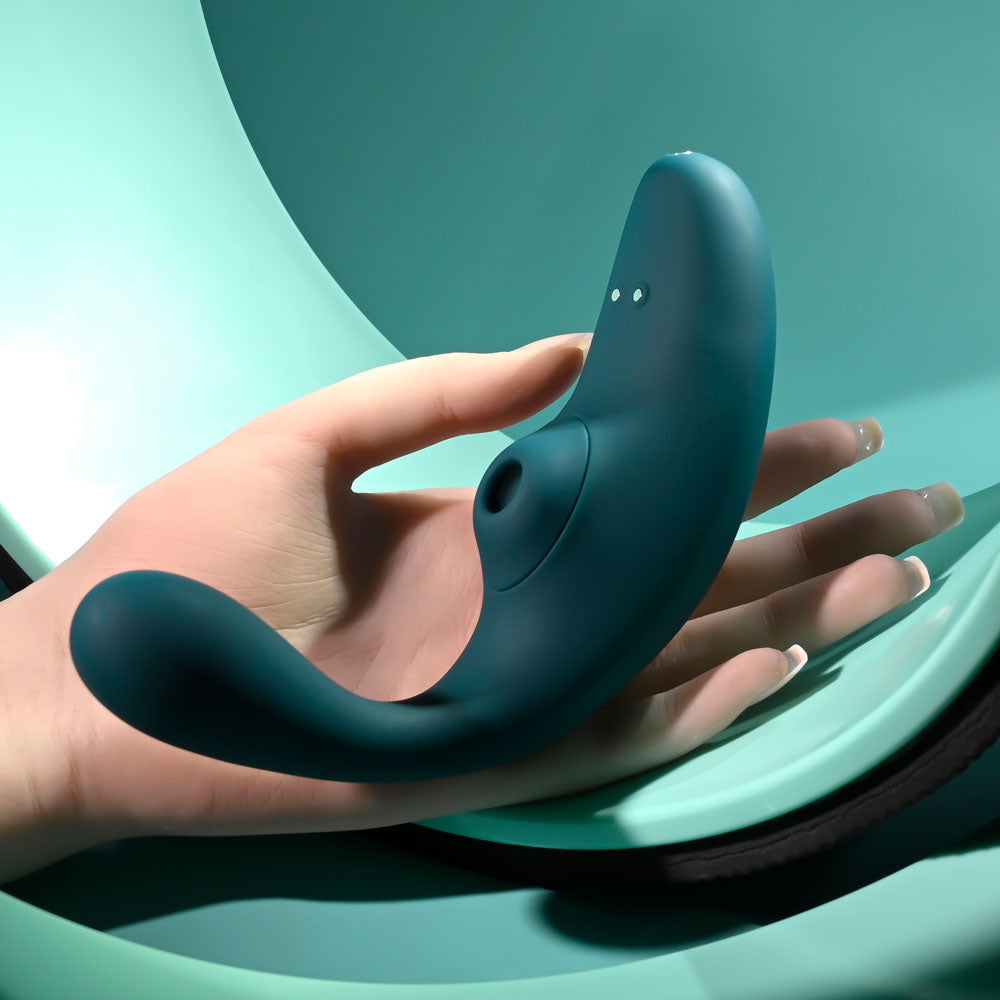 Playboy Pleasure CHARMER -  USB Rechargeable Vibrator with Clitoral Suction held in hand on a light teal background.