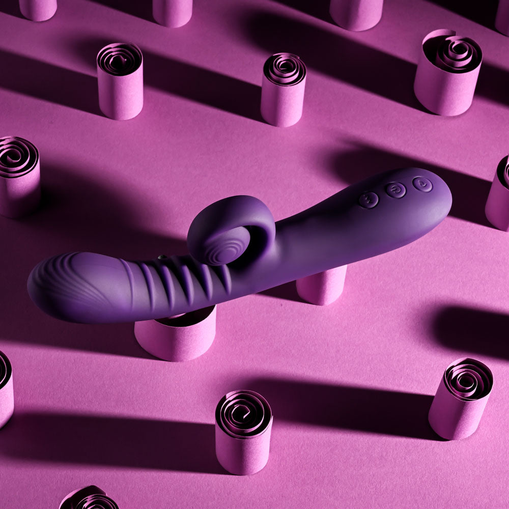Playboy CURLICUE - 23.5 cm USB Rechargeable Rabbit Vibrator on a pink background with decorative rolls.