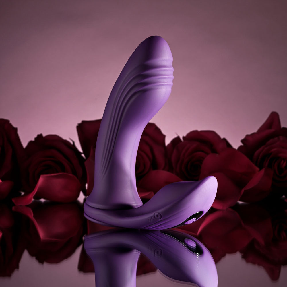 USB rechargeable vibrating C-ring on a reflective surface with rose petals in the background.