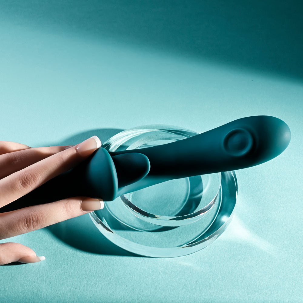 Playboy Pleasure HARMONY - 22.9 cm USB Rechargeable Vibrator with Clitoral Flicker resting on a glass base.