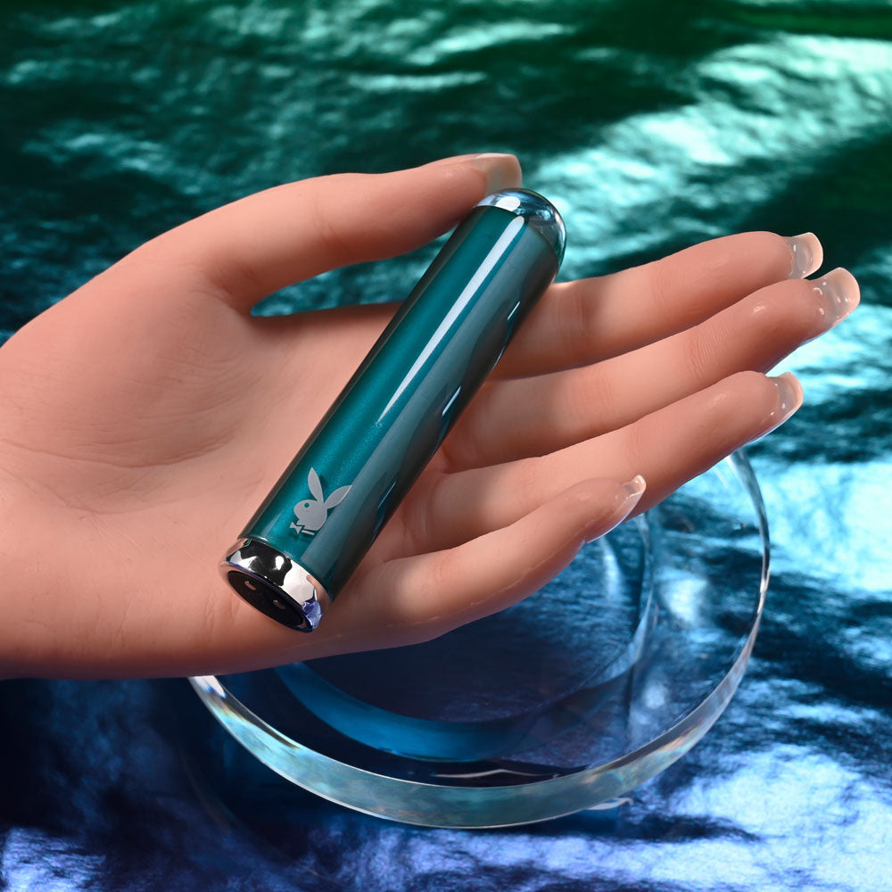 Playboy Pleasure EMERALD -  9.1 cm USB Rechargeable Glass Tipped Bullet held in a hand over a reflective surface.