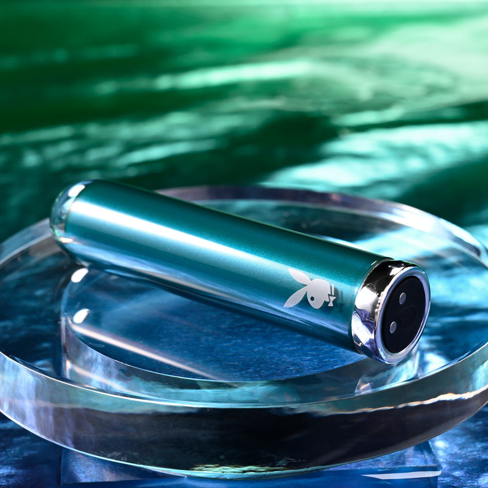 Playboy Pleasure EMERALD -  9.1 cm USB Rechargeable Glass Tipped Bullet placed on a glass surface.