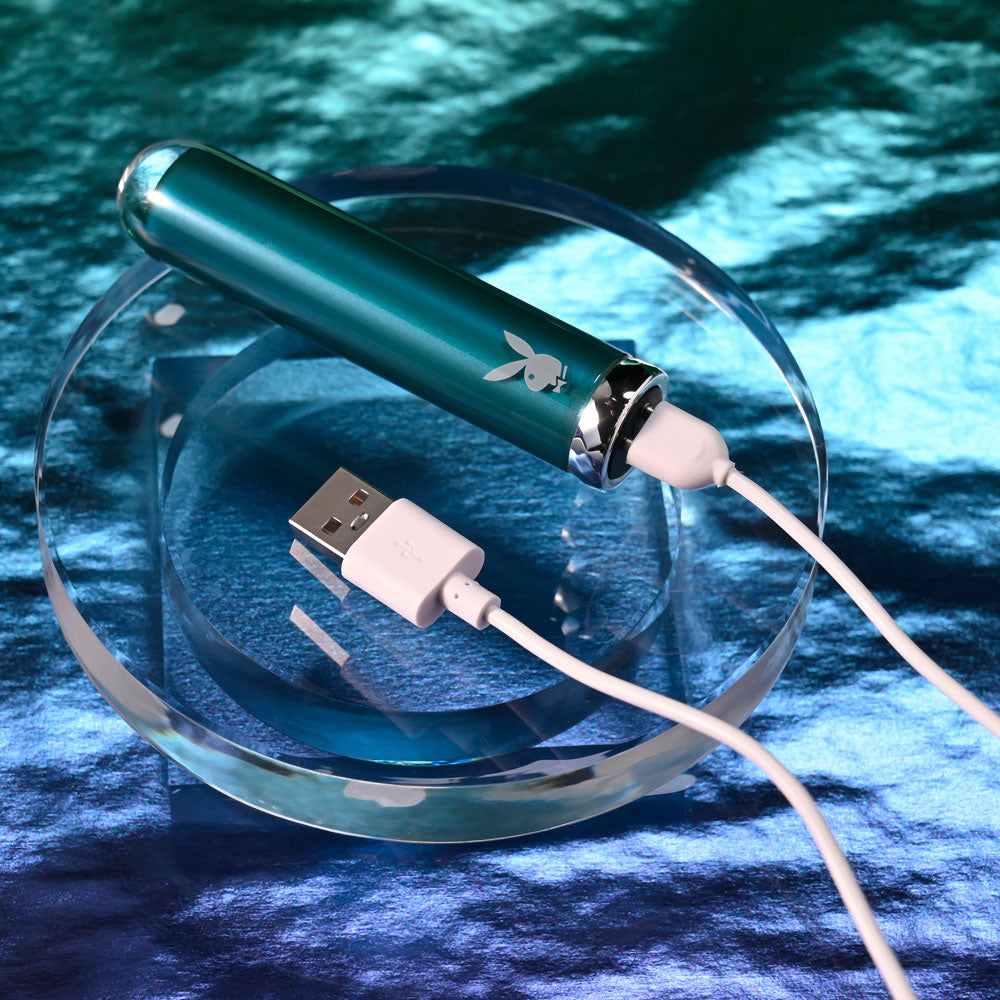 Playboy Pleasure EMERALD -  9.1 cm USB Rechargeable Glass Tipped Bullet on a reflective surface with charging cable.