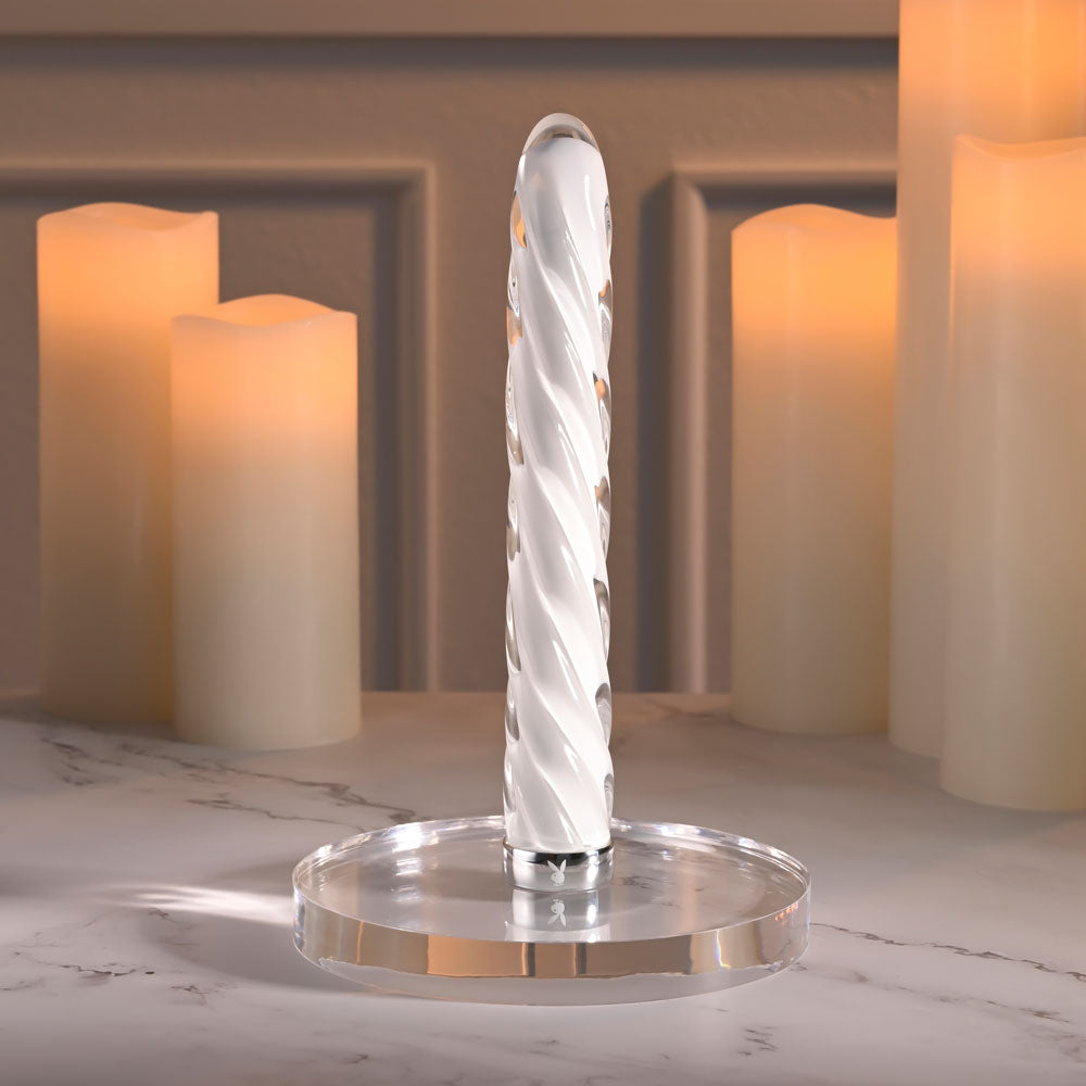 Playboy Pleasure IN A TWIST - Glass 17.5 cm USB Rechargeable Vibrator with spiral design, displayed among candles.