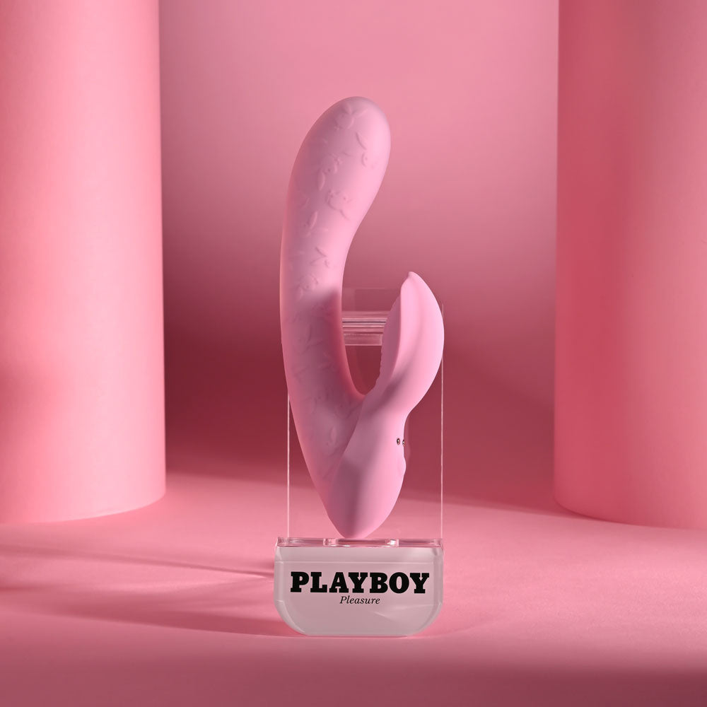Playboy Pleasure USB rechargeable rabbit vibrator displayed against a pink background.