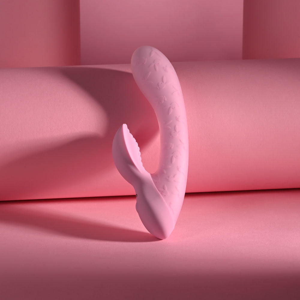USB rechargeable rabbit vibrator in a soft pink color, showcasing its dual-shaft design against a pastel background.