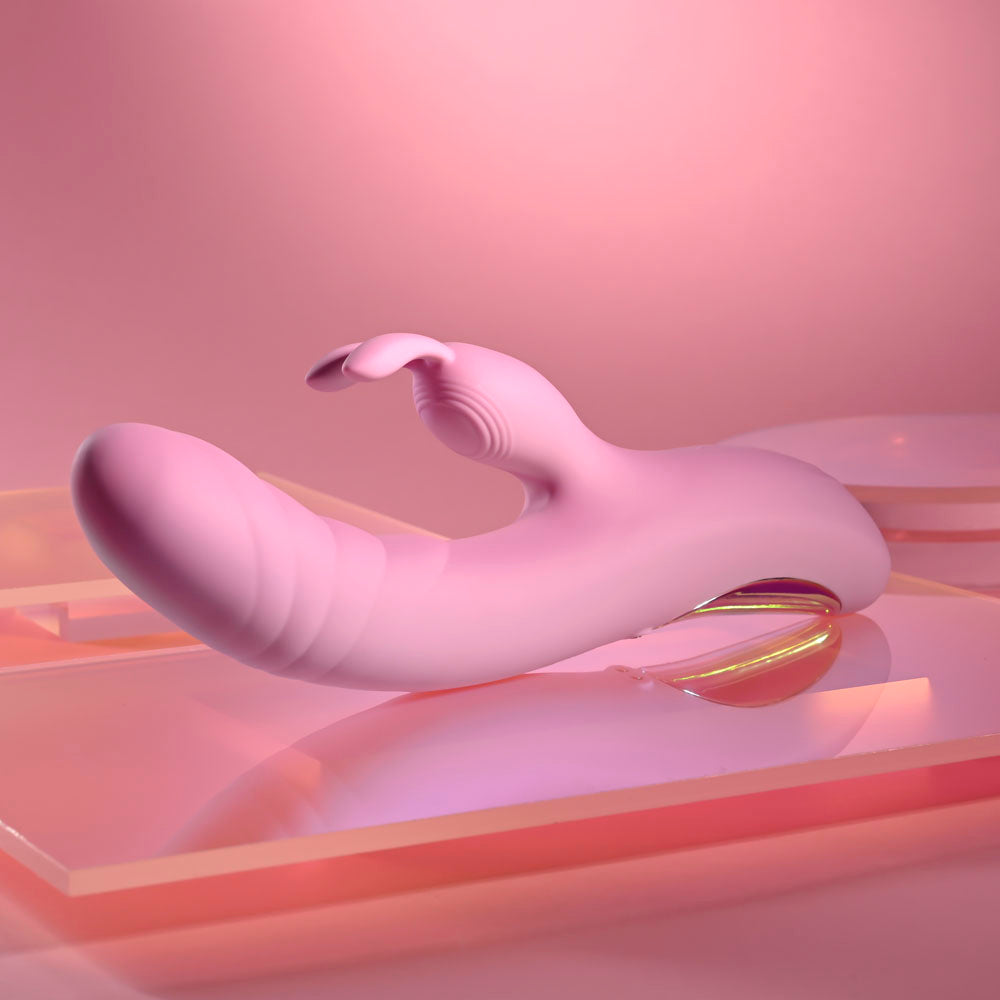 Playboy Pleasure RUB ME RIGHT - 23.2 cm USB Rechargeable Thrusting Rabbit Vibrator on a pink background.