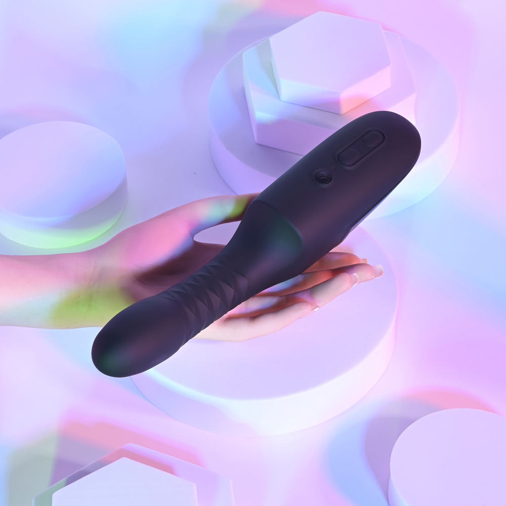Playboy Pleasure OVERDRIVE - 28.2 cm USB rechargeable thrusting vibrator held in hand against colorful background.