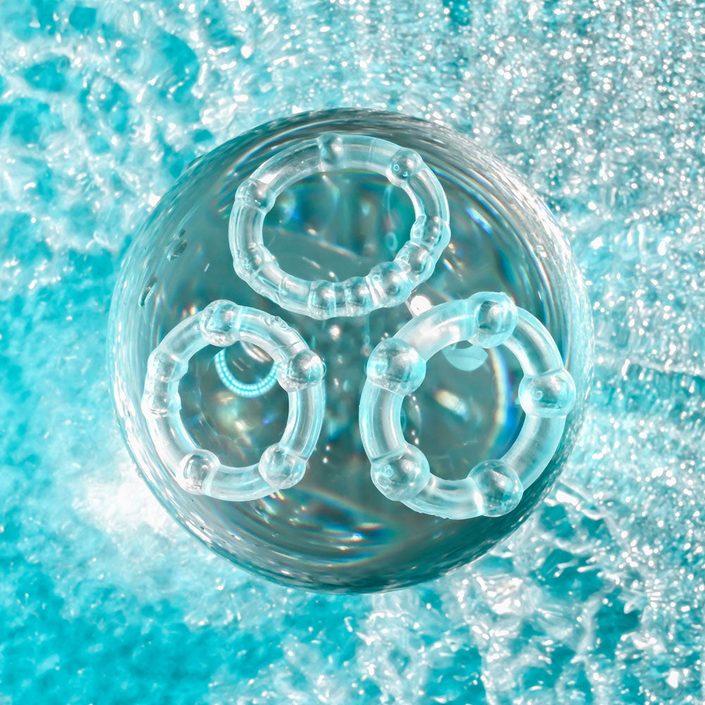 Selopa ERECTION RINGS -  Cock Rings - Set of 3 displayed on a shimmering blue surface, showcasing their unique designs.