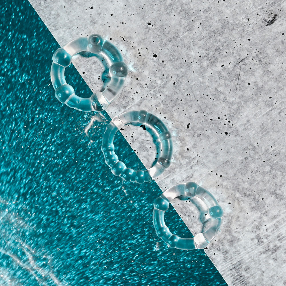 Selopa ERECTION RINGS -  Cock Rings - Set of 3 arranged on a textured surface with a vibrant blue background.