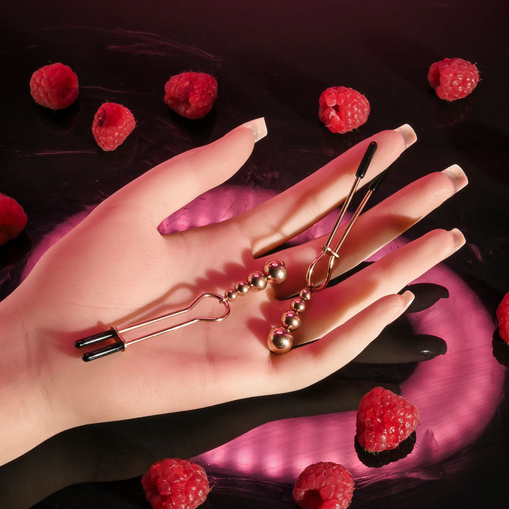 Selopa BEADED NIPPLE CLAMPS -  -  Nipple Clamps - Set of 2 on a hand with raspberries in the background.
