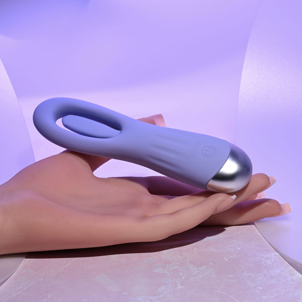 Selopa IN A FLAP - 15 cm USB Rechargeable Flicking Stimulator held in hand on a pastel background.