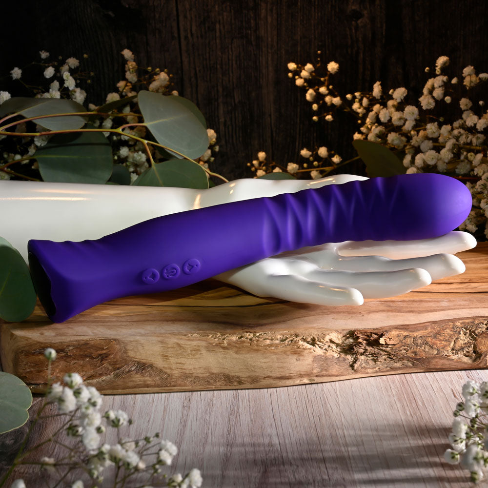 Selopa TRIXXXIE - 22.2 cm USB Rechargeable Vibrator on a wooden surface surrounded by flowers and decor.