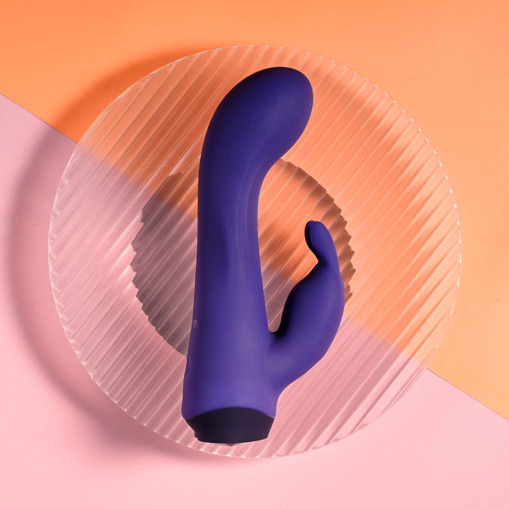 Selopa PLUM JOB -  13.5 cm USB Rechargeable Rabbit Vibrator on a circular plate with colored background.