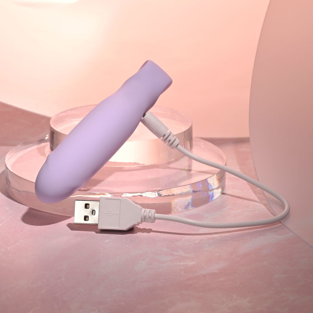 Selopa PETITE PECKER -  11.7 cm USB Rechargeable Mini Vibrator with charging cable on a pastel background.