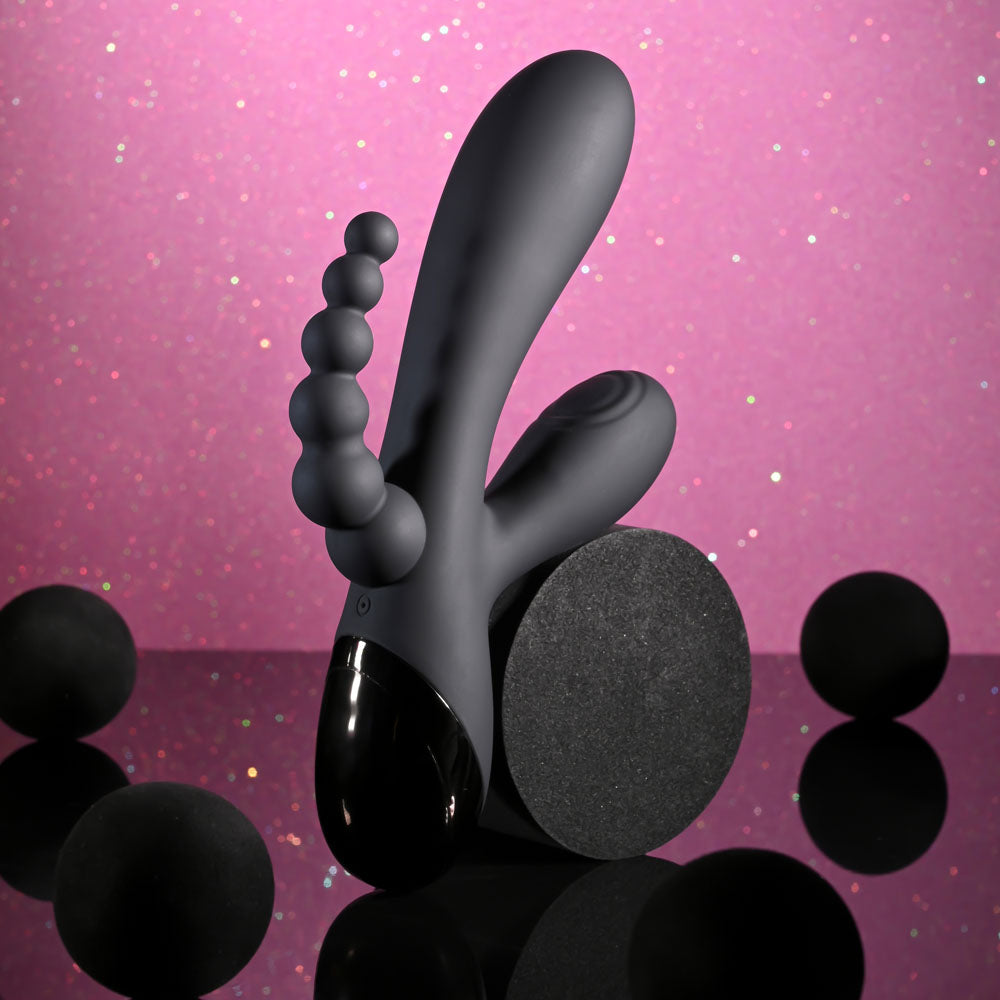 Selopa TRIPLE ACES - 19.7 cm USB Rechargeable Triple Stimulator Vibrator on a reflective surface with decorative spheres.
