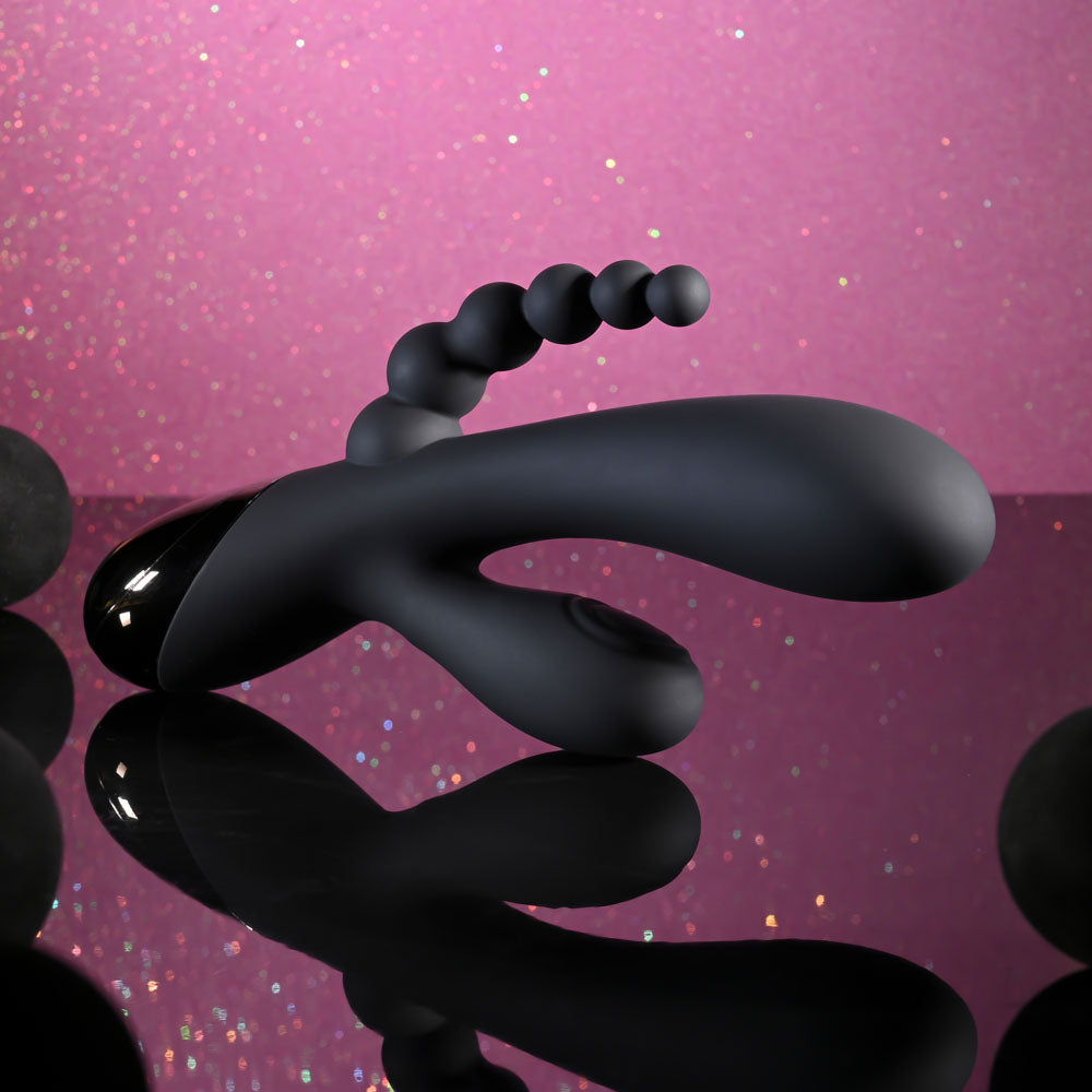 Selopa TRIPLE ACES - 19.7 cm USB Rechargeable Triple Stimulator Vibrator against sparkling pink background.