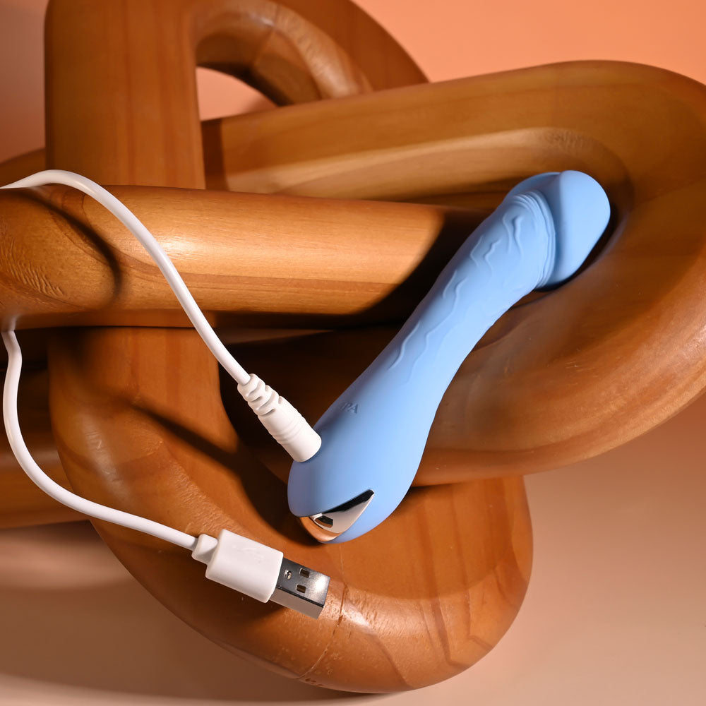 Selopa DAINTY DICK - Baby 11.9 cm USB Rechargeable Mini Vibrator charging on a wooden surface.