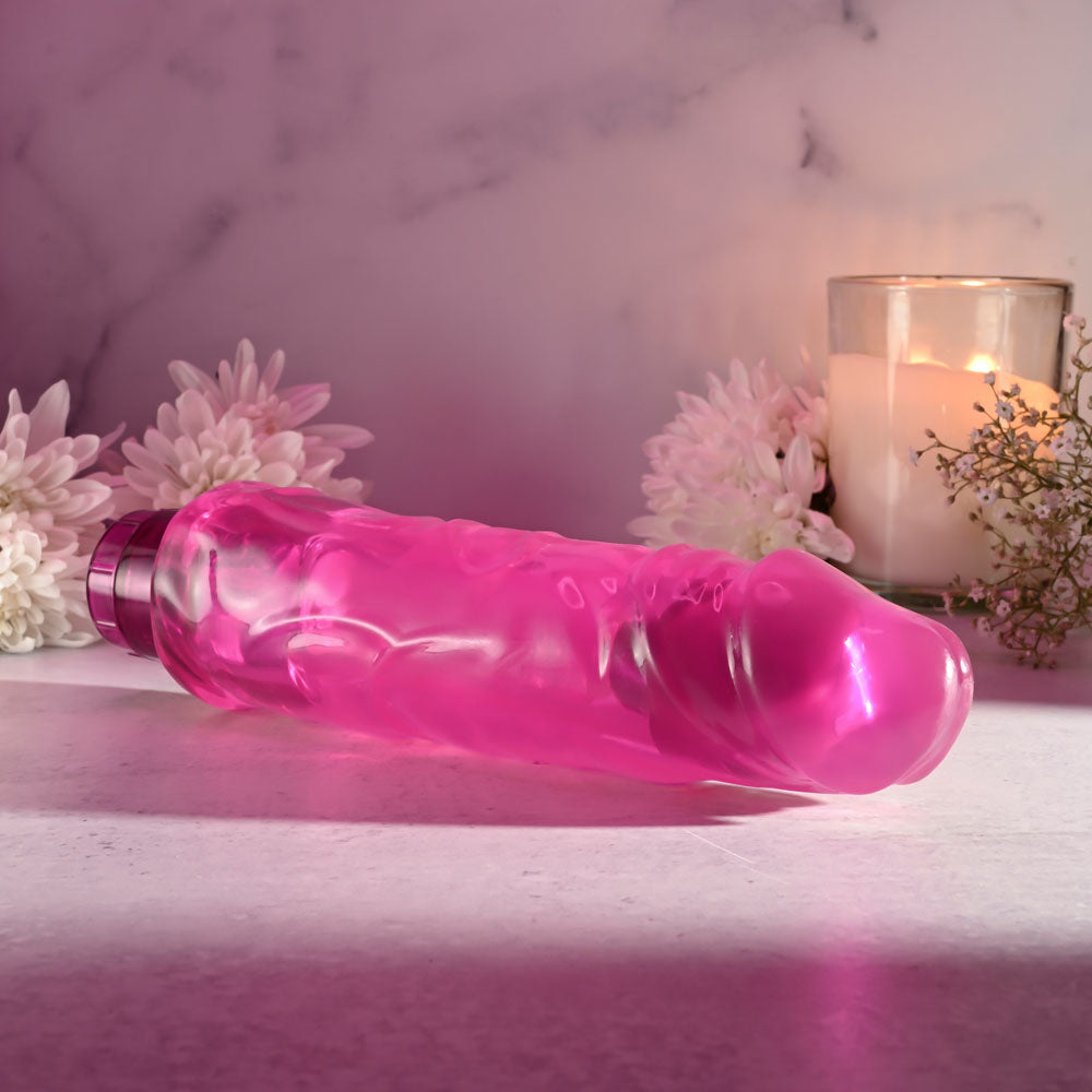 Selopa THICC BOI - 22.9 cm Vibrator displayed on a smooth surface with flowers and candle in the background.