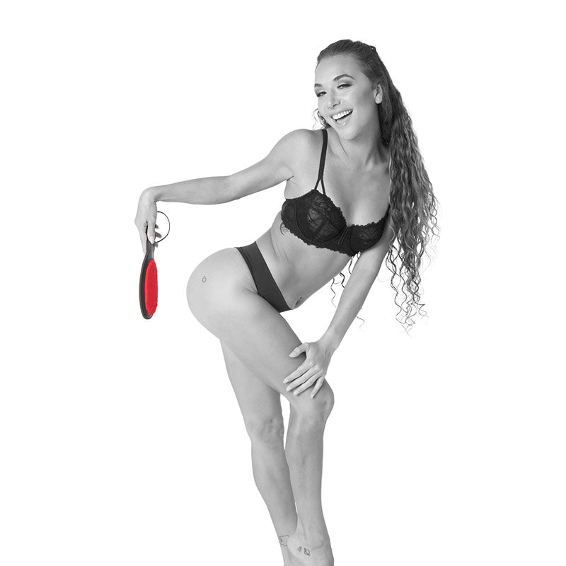 Model holding the Sex & Mischief Amor Paddle - /Black Spanking Paddle, showcasing its playful use in intimate settings.