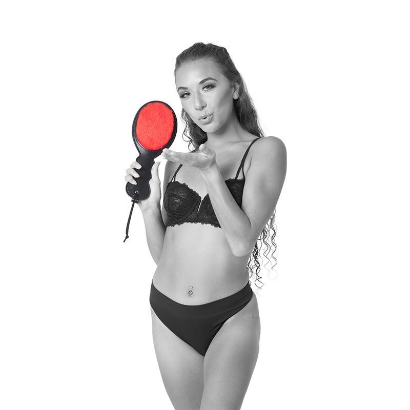 Model showcasing the Sex & Mischief Amor Paddle - /Black Spanking Paddle, teasing with its soft and fuzzy side.