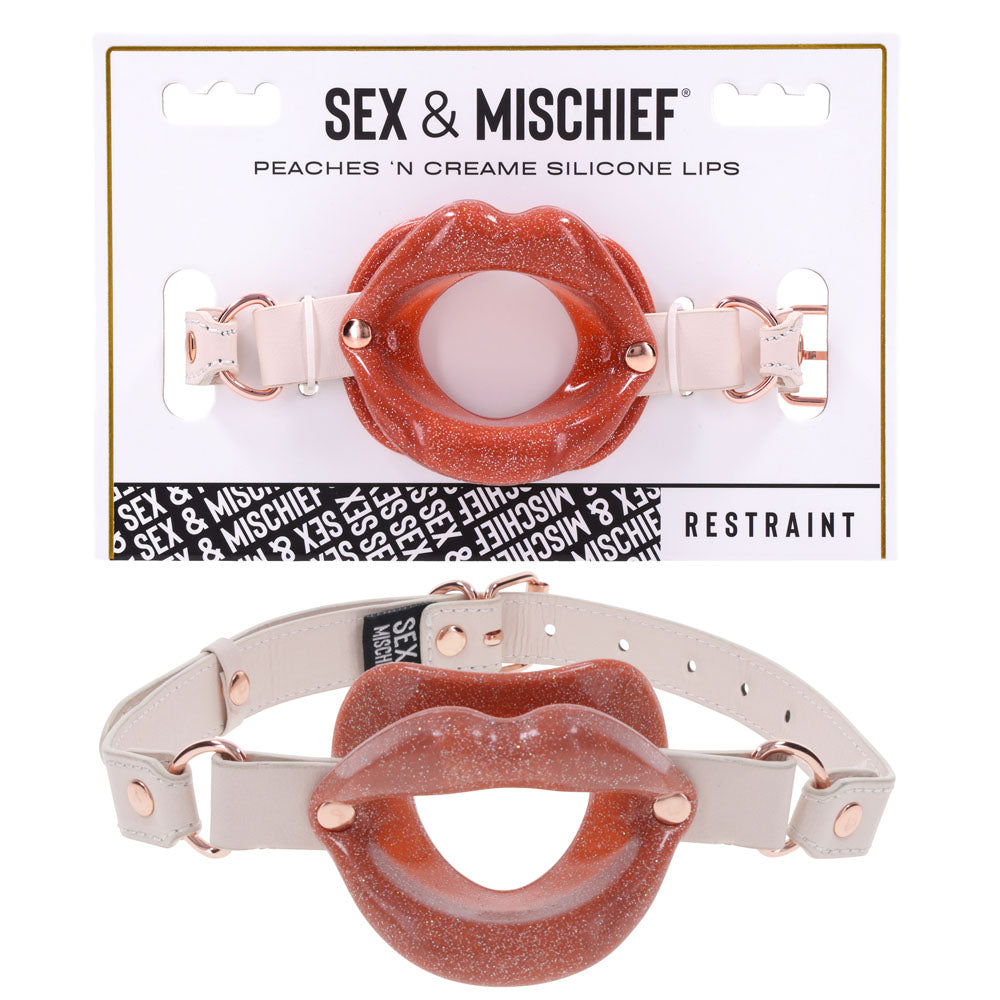Sex & Mischief Peaches n CreaMe Silicone Lips - Peach Mouth Restraint on display with packaging and strap.