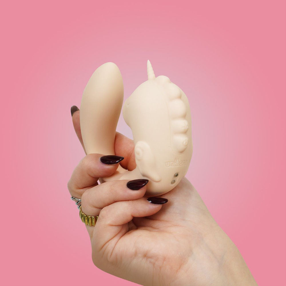 Unihorn - C Horse - Coral Throb - Coral USB Rechargeable Dual Unicorn Vibrator in hand against pink background.