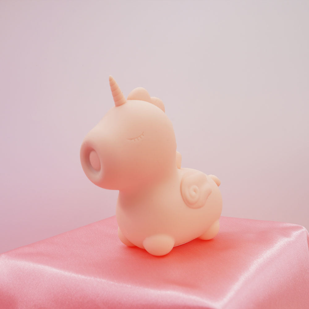 Unihorn - Heart Throb - Coral USB Rechargeable Flicking Stimulator on a pink satin background.