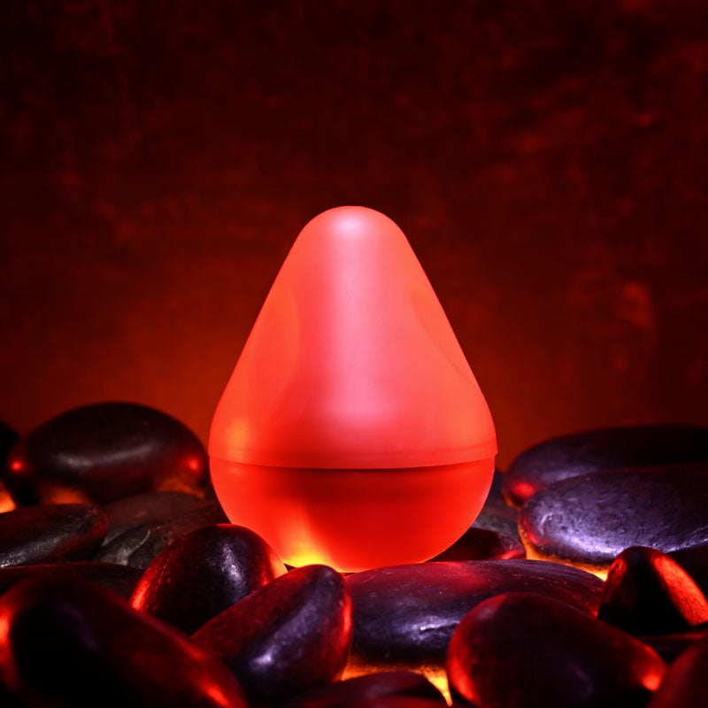 Zero Tolerance KILAUEA - Mini Stroker Egg displayed on smooth rocks with a glowing red background.
