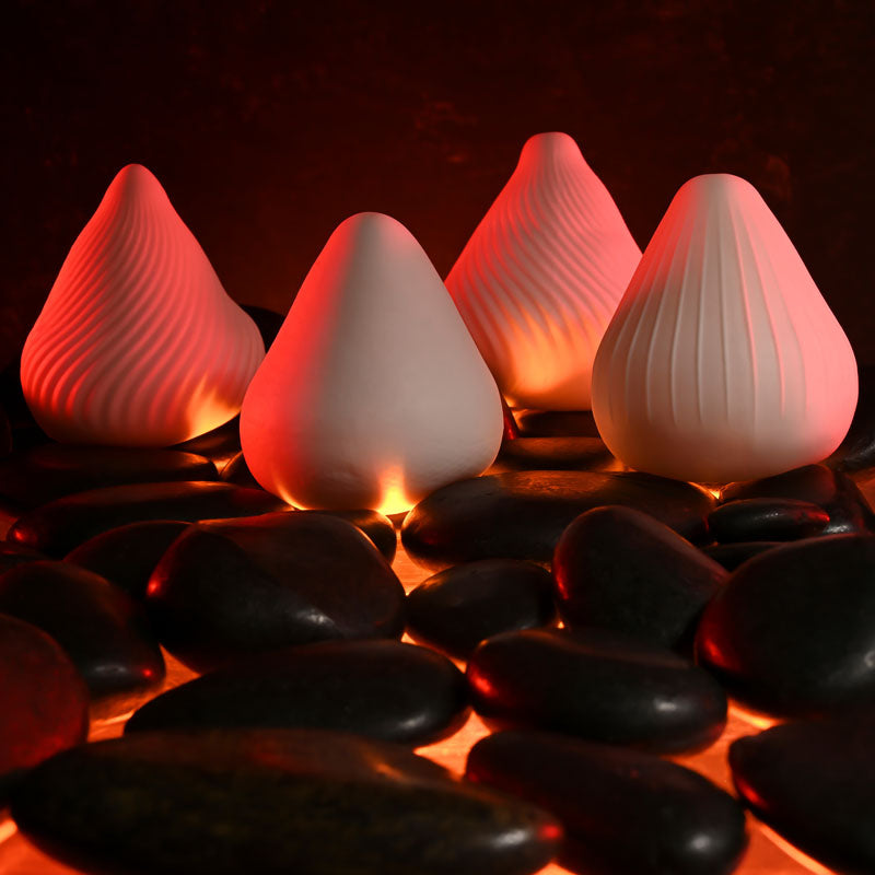 Zero Tolerance KILAUEA - Mini Stroker Egg displayed among smooth stones with soft red glow.