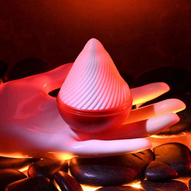 Zero Tolerance VESUVIUS -  Mini Stroker Egg resting on a hand surrounded by smooth stones and warm lighting.